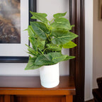 Artificial Elephant Ear plant with broad green leaves in a white ribbed PVC pot.