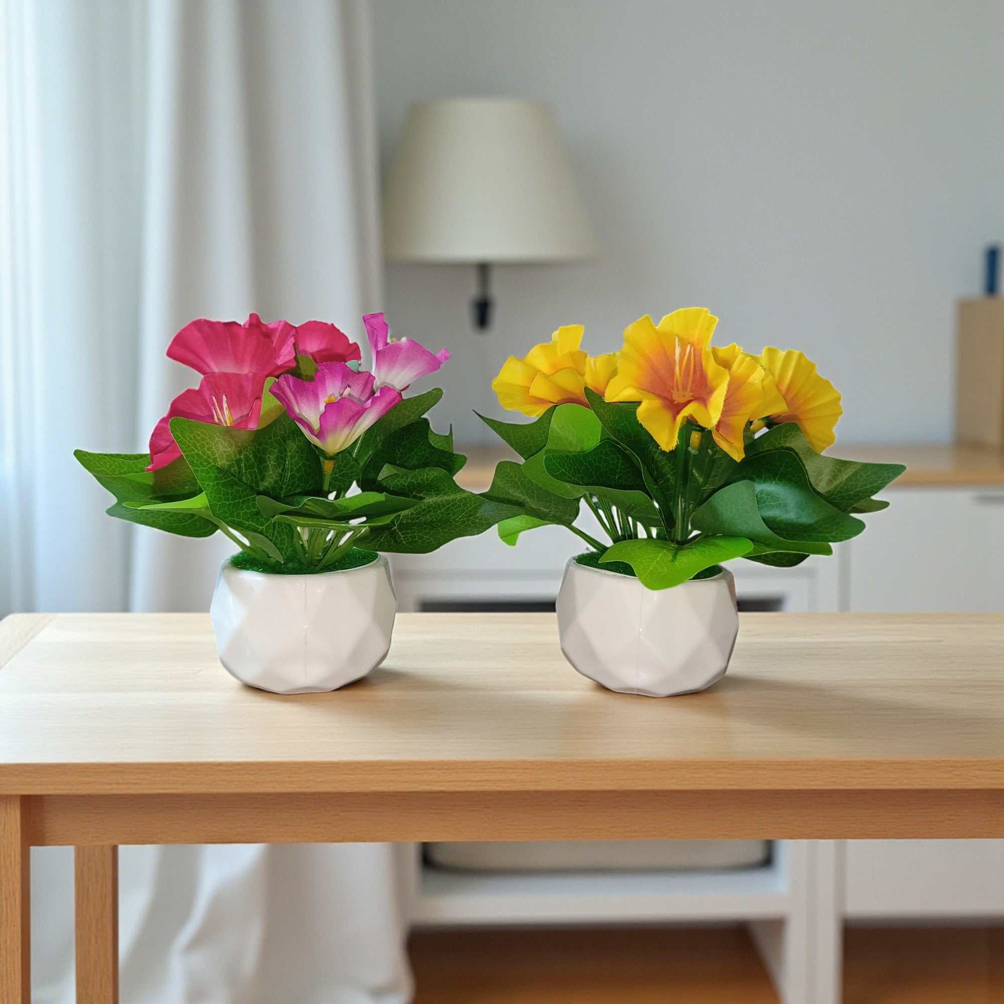 Set of two small artificial morning glory flower pots featuring pink and yellow blossoms in white geometric diamond-cut ceramic planters.