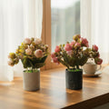 Set of two small artificial rose bud plants in light and dark grey speckled pots.