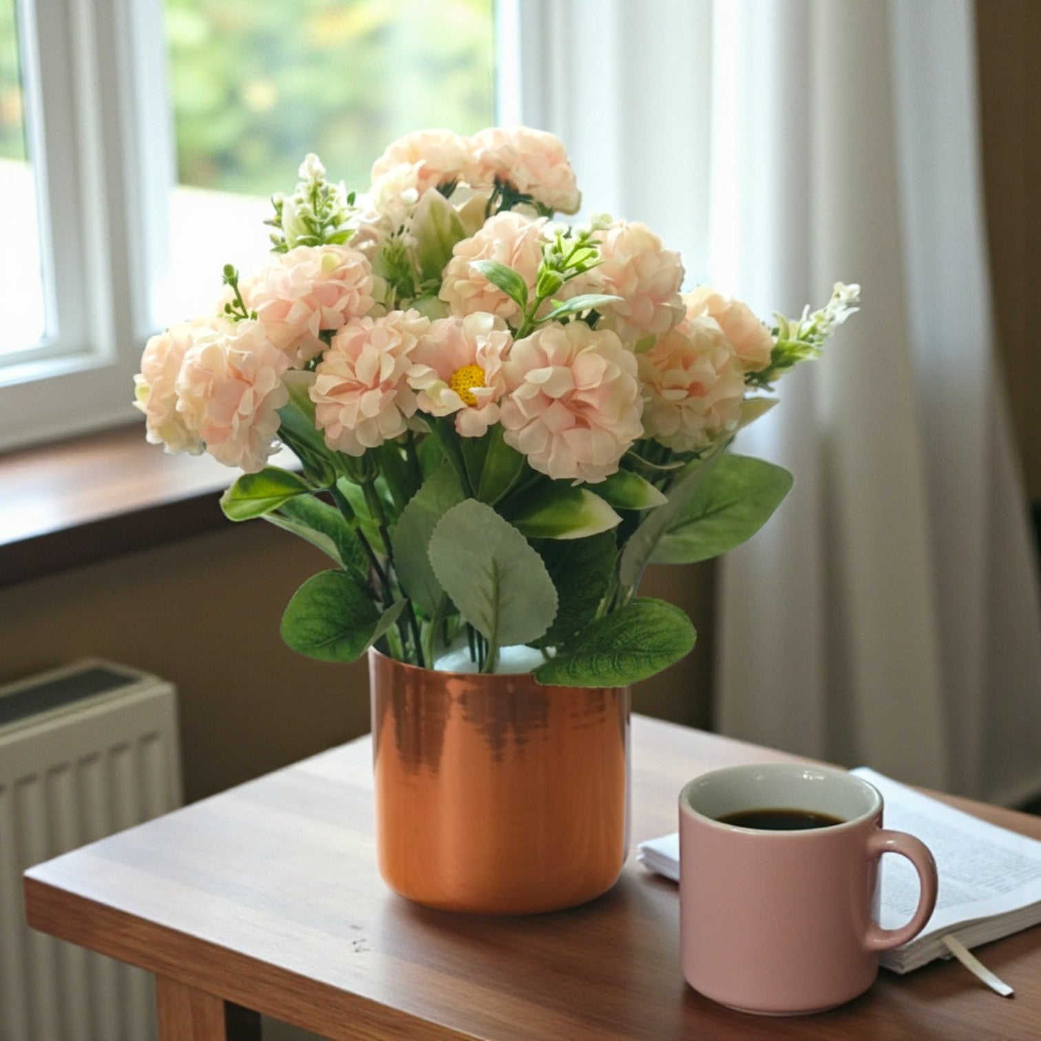 Artificial peach-colored flowers arranged in a cylindrical copper metal pot.