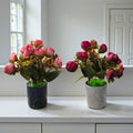 Set of two small artificial rose bud plants featuring magenta flowers in a dark speckled pot and deep pink flowers in a light speckled pot.